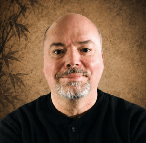 Portrait of Mark V. Wiley, martial artist, author, and researcher, on a warm textured background.